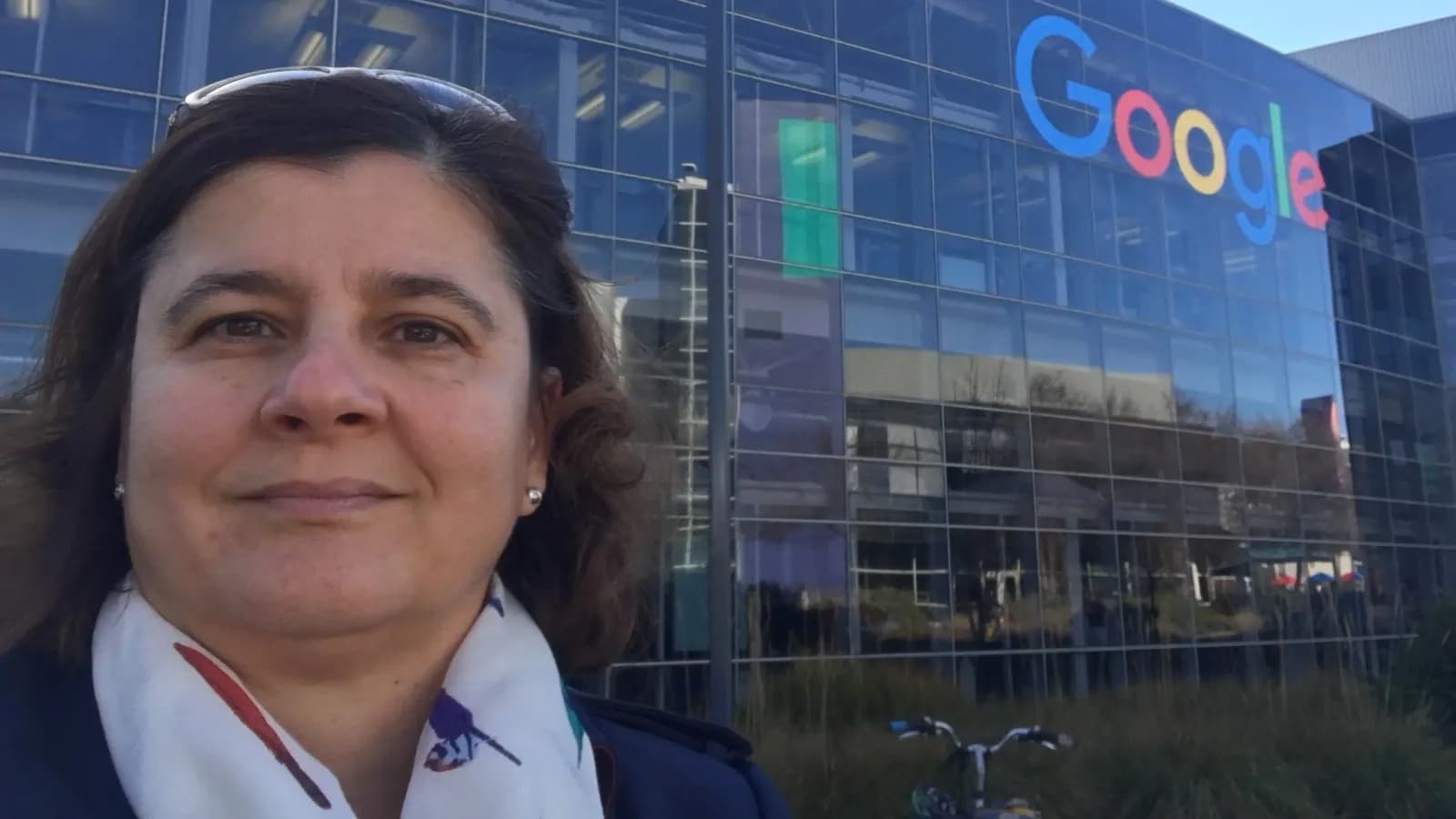 Vera Ingallati outside a Google campus building, its glass facade carrying the Google logo behind her.